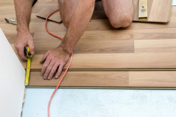 Image depicts a flooring expert installing wood floors in a Ottawa home.